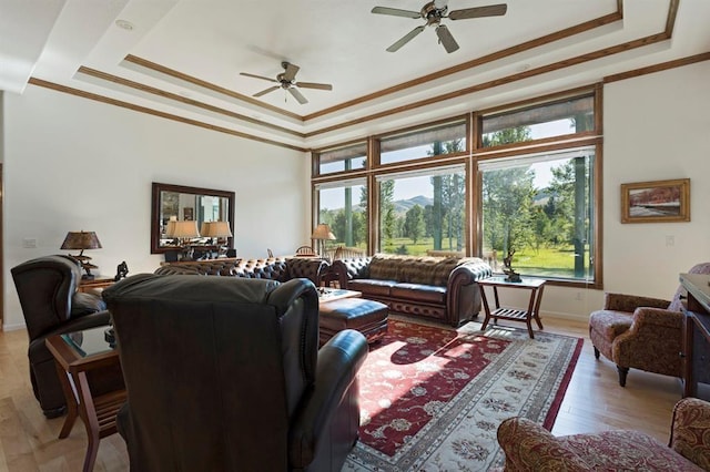 living room with a tray ceiling, ceiling fan, crown molding, and hardwood / wood-style flooring