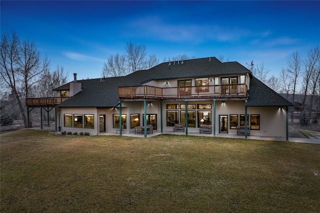 back house at dusk featuring a lawn, a patio area, and a wooden deck