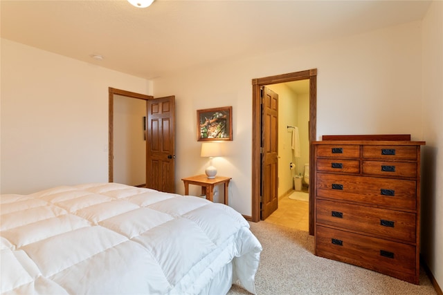 bedroom with ensuite bathroom and light colored carpet