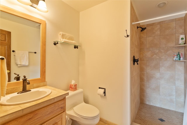 bathroom with vanity, toilet, and tiled shower