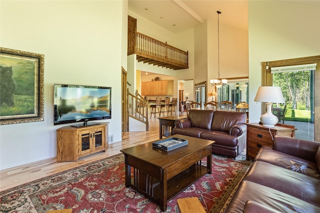 living room with a high ceiling, an inviting chandelier, and wood-type flooring