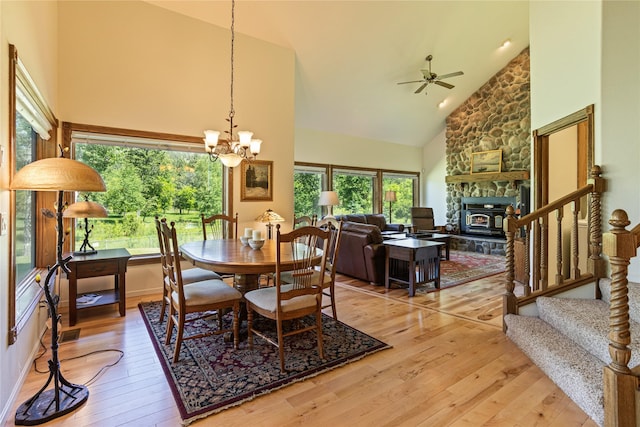 dining area featuring high vaulted ceiling, ceiling fan with notable chandelier, and light wood-type flooring