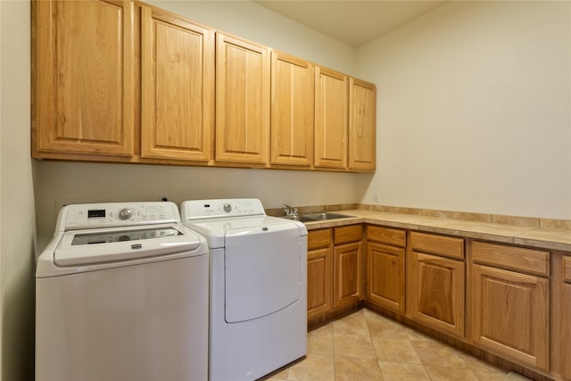 laundry area featuring washer and clothes dryer, sink, light tile patterned floors, and cabinets