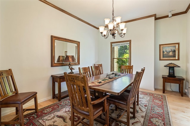 dining room with light hardwood / wood-style flooring, ornamental molding, and a notable chandelier