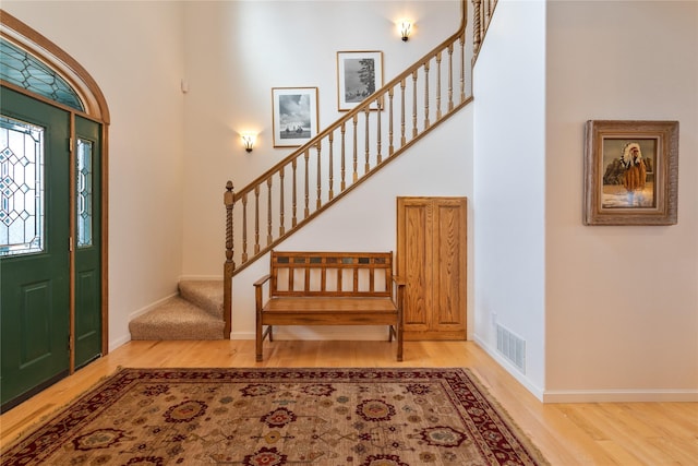 foyer featuring wood-type flooring and a towering ceiling