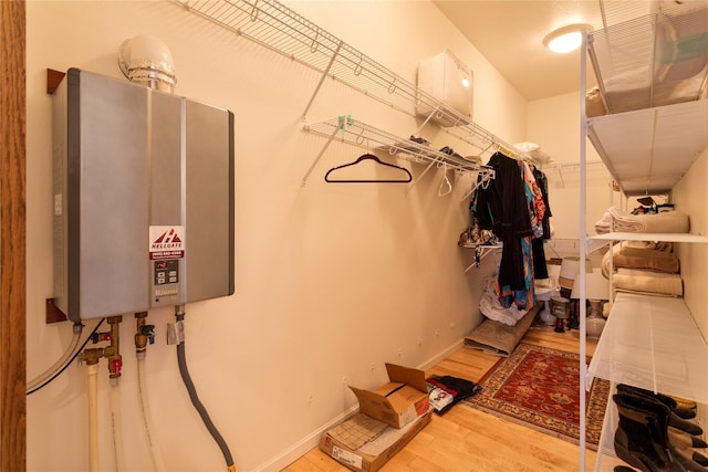 spacious closet featuring tankless water heater and wood-type flooring