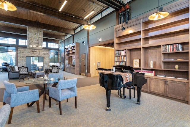 carpeted home office with a stone fireplace, beamed ceiling, wood ceiling, and a high ceiling