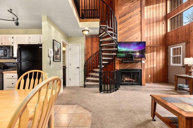 carpeted living room with wooden walls, baseboard heating, and a high ceiling