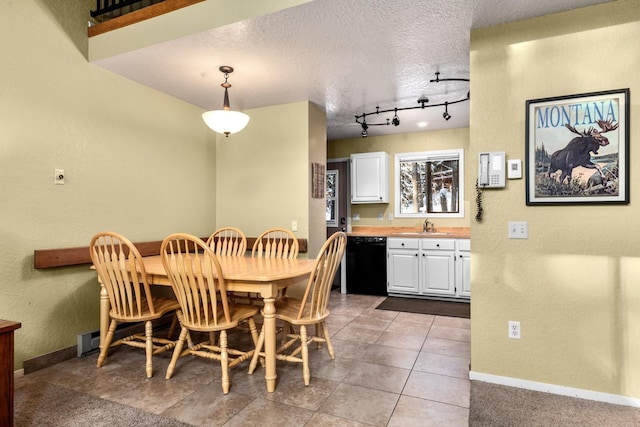 tiled dining area featuring a textured ceiling, track lighting, and sink