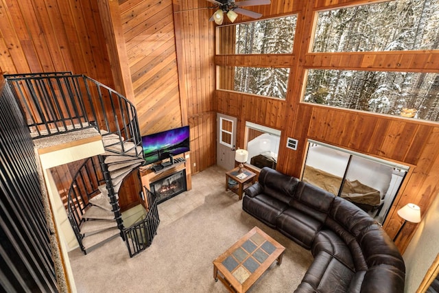 carpeted living room with ceiling fan and a high ceiling