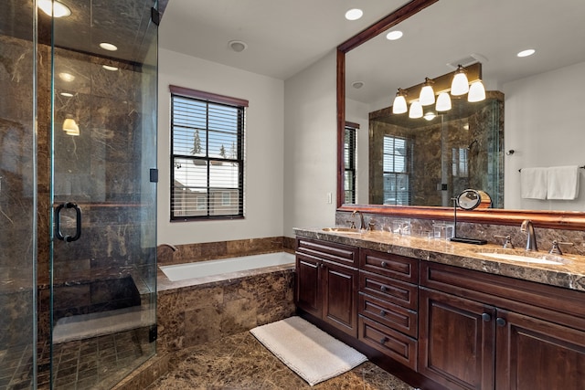 bathroom featuring oversized vanity, a healthy amount of sunlight, double sink, and plus walk in shower