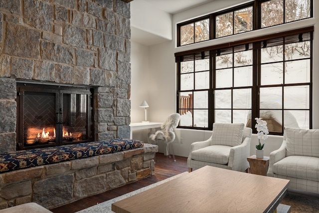 living room with dark hardwood / wood-style floors and a stone fireplace