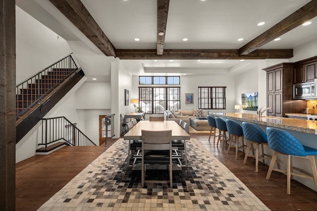 dining room featuring sink, beam ceiling, and dark wood-type flooring