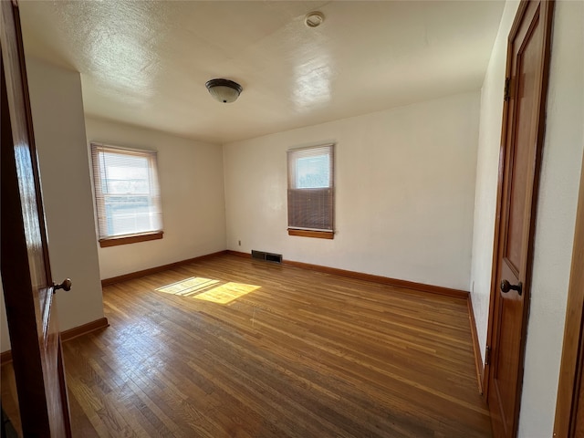 spare room featuring a healthy amount of sunlight and dark wood-type flooring