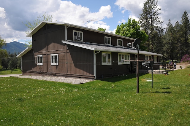 rear view of house with cooling unit, a mountain view, and a yard