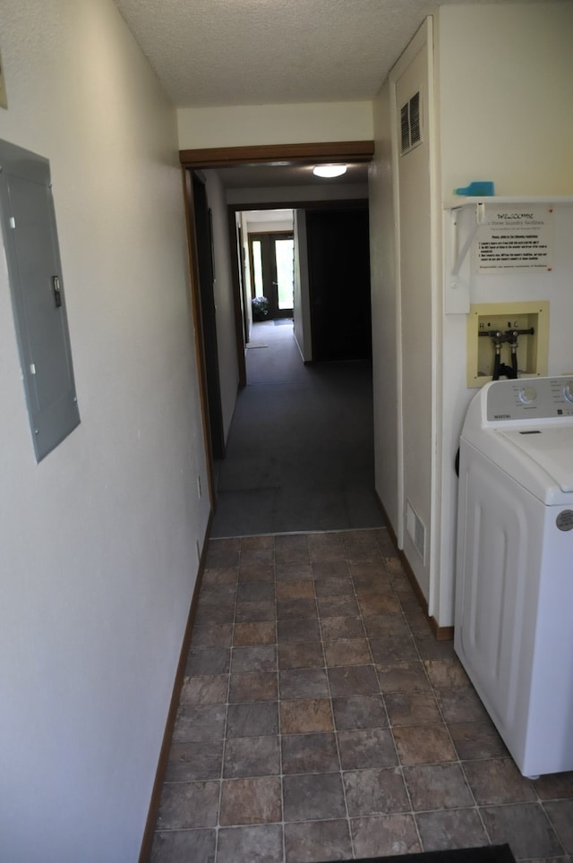 corridor with a textured ceiling, electric panel, and washer / clothes dryer