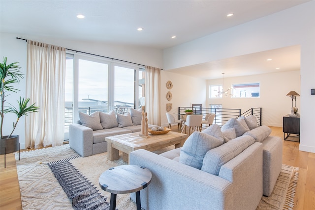 living room with an inviting chandelier, light hardwood / wood-style flooring, and a healthy amount of sunlight