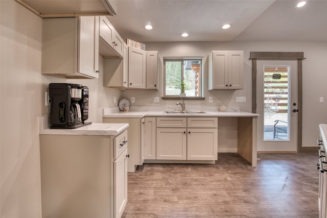 kitchen with light hardwood / wood-style flooring, white cabinetry, and sink