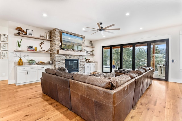 living room featuring ceiling fan, a fireplace, and light hardwood / wood-style flooring