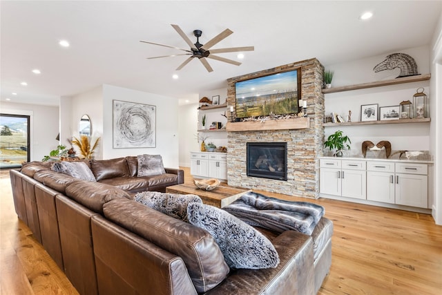 living room with a fireplace, ceiling fan, and light wood-type flooring