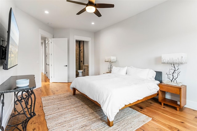 bedroom with ceiling fan, light wood-type flooring, and connected bathroom