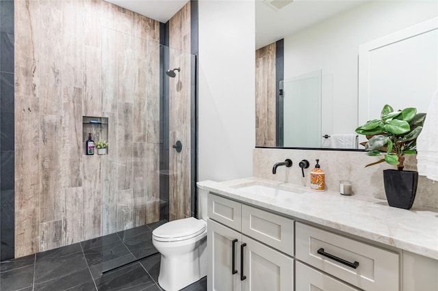 bathroom with toilet, vanity, a tile shower, and tasteful backsplash