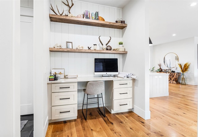 office space with built in desk and light hardwood / wood-style floors