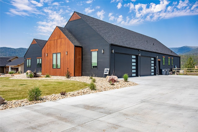 view of home's exterior with a mountain view, a garage, and a lawn