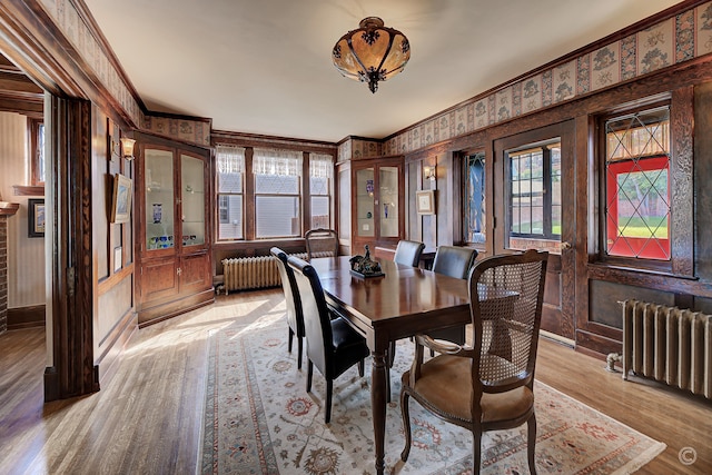 dining space featuring ornamental molding, light hardwood / wood-style floors, and radiator heating unit