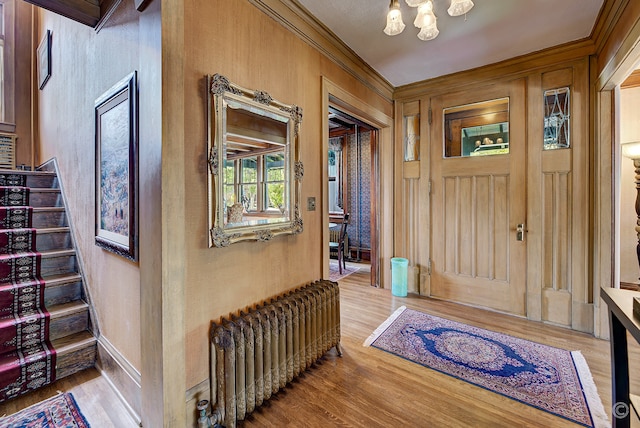 foyer with light hardwood / wood-style flooring, a notable chandelier, radiator, and ornamental molding