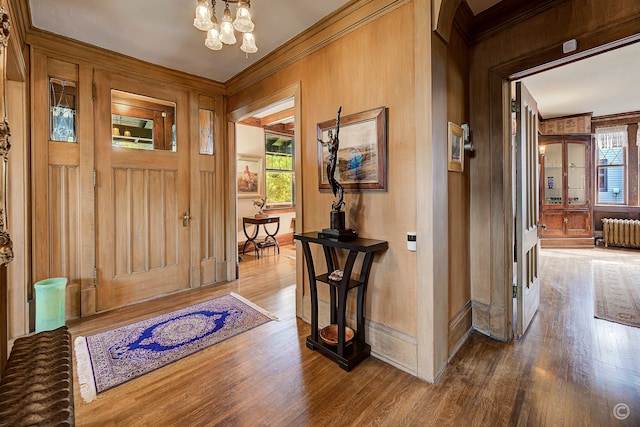 entrance foyer featuring hardwood / wood-style floors, a notable chandelier, crown molding, and radiator