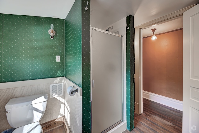 bathroom featuring wood-type flooring, a shower with shower door, and toilet