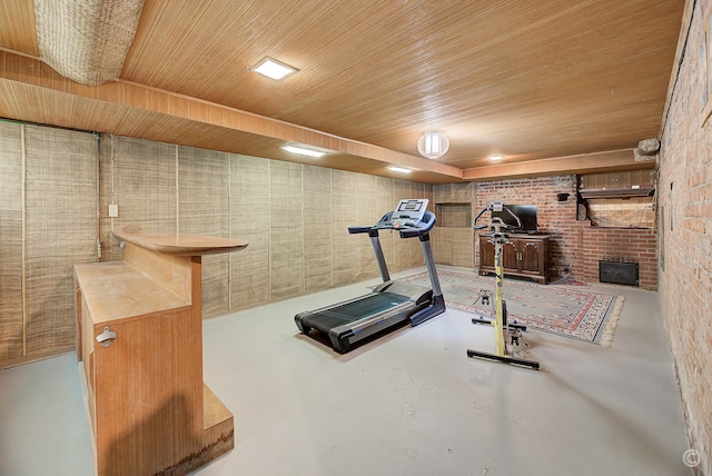 workout room with wood ceiling, concrete flooring, and brick wall