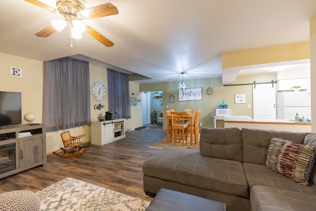 living room featuring dark hardwood / wood-style flooring, ceiling fan, and a barn door