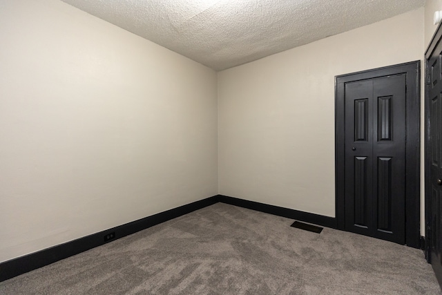 spare room with a textured ceiling and carpet flooring