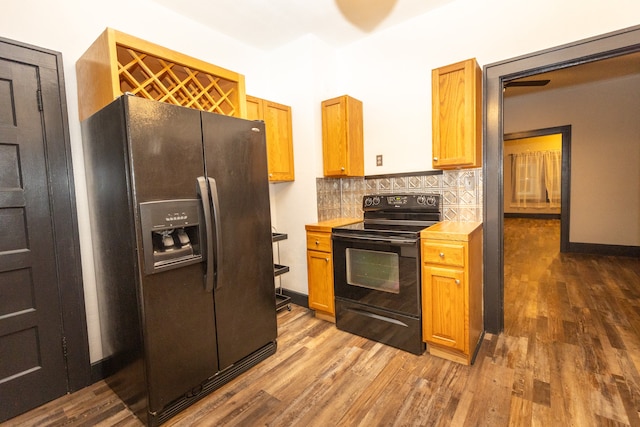 kitchen featuring black appliances, wood-type flooring, and backsplash