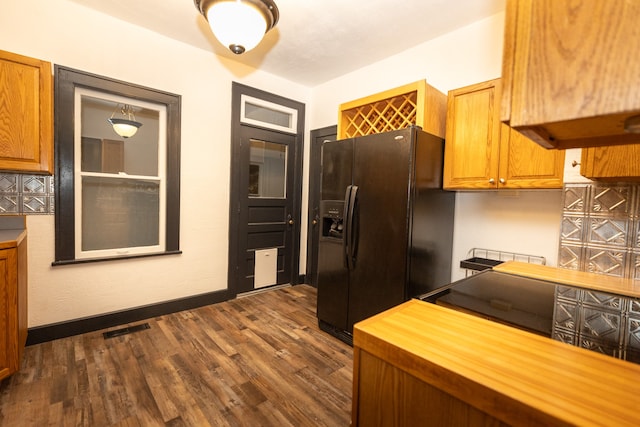 kitchen with black fridge, dark wood-type flooring, tasteful backsplash, and butcher block countertops