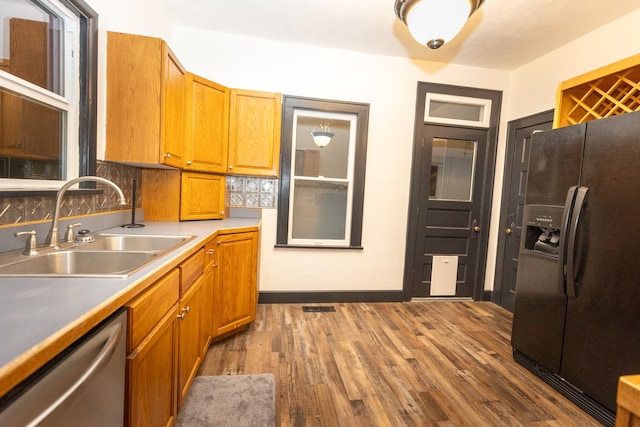 kitchen with black fridge, hardwood / wood-style floors, sink, and stainless steel dishwasher