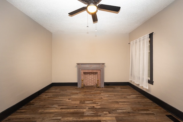 unfurnished room featuring a brick fireplace, ceiling fan, dark hardwood / wood-style flooring, and a textured ceiling