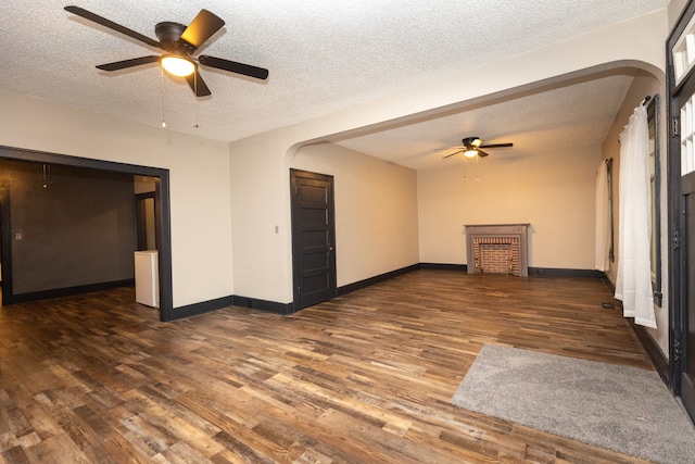 unfurnished living room with a textured ceiling, dark wood-type flooring, and ceiling fan