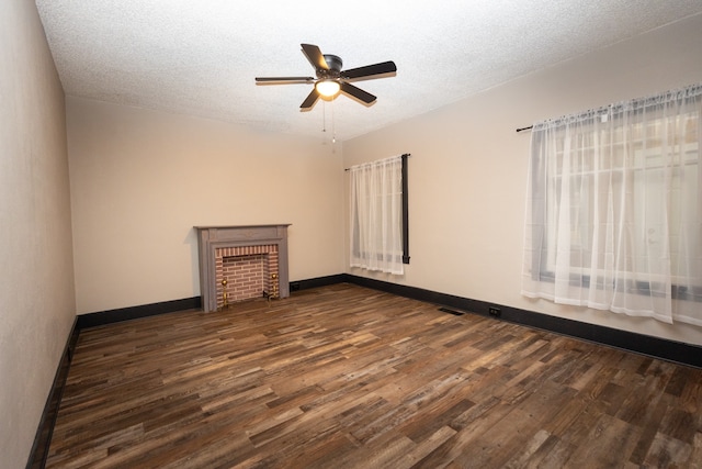 unfurnished living room featuring a textured ceiling, a brick fireplace, and dark hardwood / wood-style floors