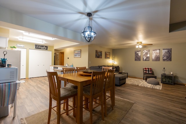 dining area with ceiling fan with notable chandelier and hardwood / wood-style floors