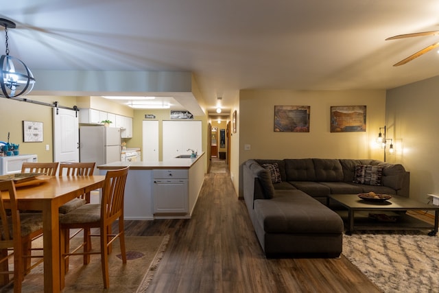 living room featuring sink, ceiling fan, a barn door, and dark hardwood / wood-style floors