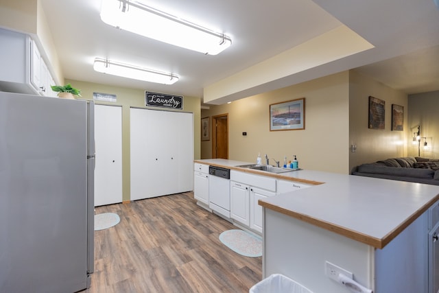 kitchen featuring white cabinets, white dishwasher, light hardwood / wood-style flooring, sink, and stainless steel fridge