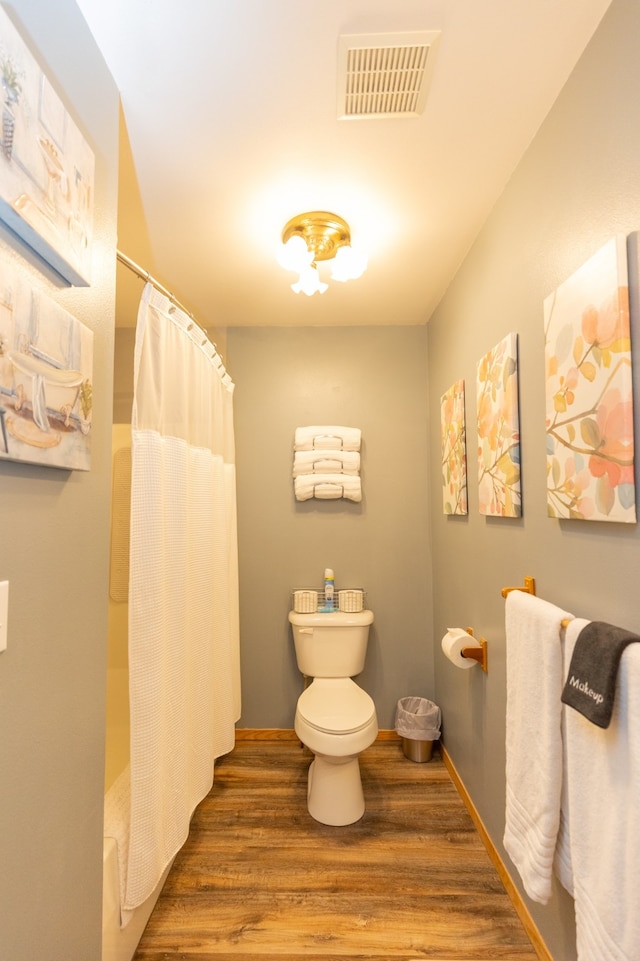 bathroom featuring toilet, curtained shower, and hardwood / wood-style flooring