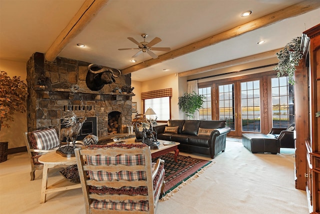 carpeted living room with a stone fireplace, ceiling fan, and beam ceiling