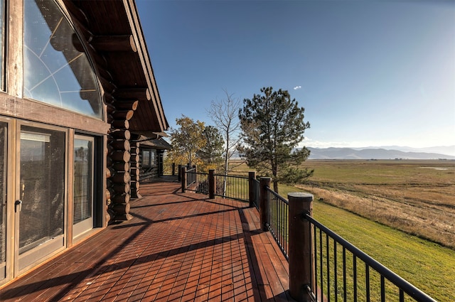 deck with a rural view, a yard, and a mountain view