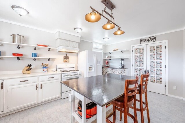 kitchen with crown molding, custom range hood, white appliances, white cabinets, and hanging light fixtures