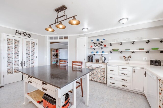 kitchen with white cabinetry, pendant lighting, light hardwood / wood-style flooring, and dishwasher