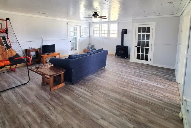 living room with ceiling fan, wood-type flooring, and a wood stove